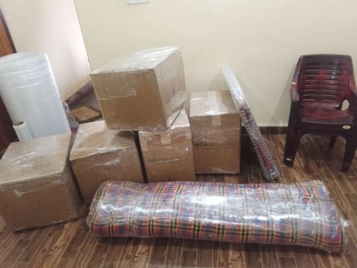 Real on-site household shifting staging for Chennai to Coimbatore move showing stretch-wrapped mattress roll, sealed corrugated cartons, folding ironing board, and industrial bubble wrap rolls