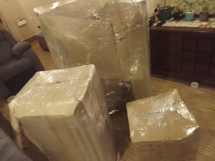 Live on-site packing in Choolaimedu Chennai showing home appliances, furniture, and carton boxes wrapped in corrugated cardboard and transparent stretch film